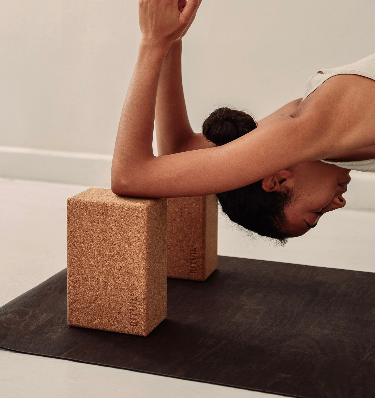 Rituil sustainable natural brown cork leather yoga mat featuring a non-slip, non-toxic, pvc free, with natural cork yoga blocks and woman practicing yoga