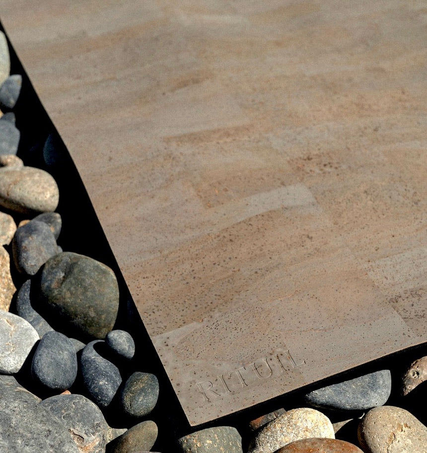 Rituil cork leather yoga mat laying on stone 