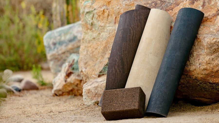 
Rituil cork yoga mats and cork yoga block in earth, sand, and slate colors leaning against natural stone