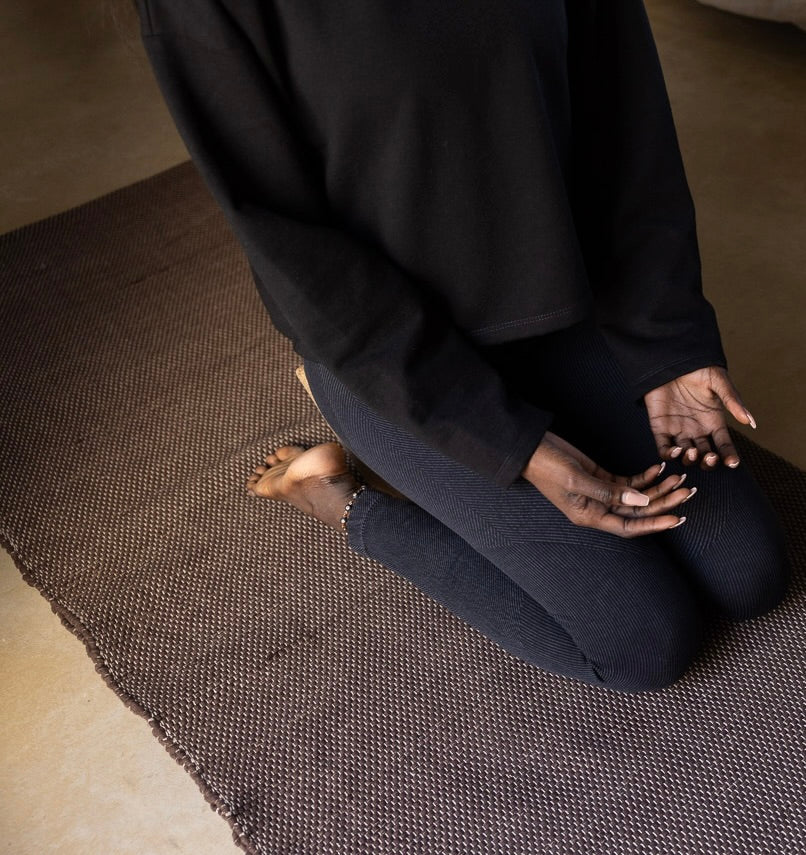 woman kneeling on Rituil cotton yoga rug and blanket
