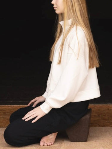 woman sitting on rituil natural cork mat and natural cork block meditating.