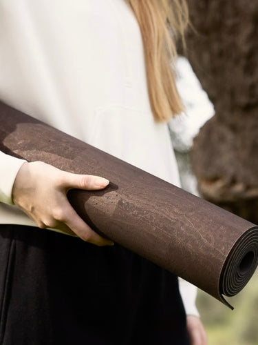 woman holding Rituil non slip earth or brown colored cork yoga mat #color_earth