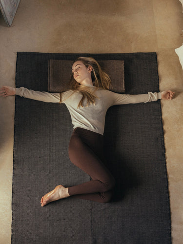 woman laying on rituil cotton yoga rug