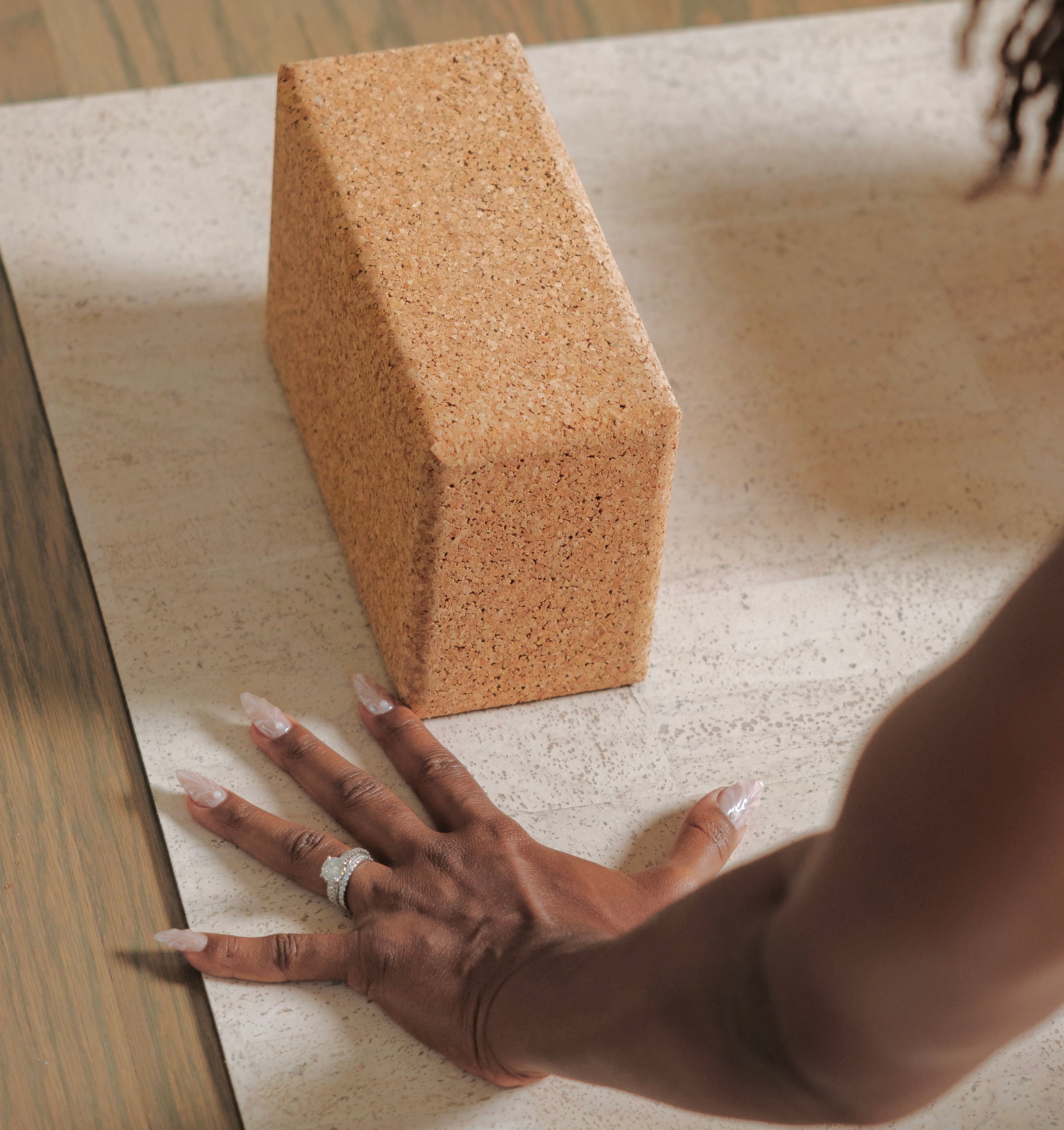 Cork yoga block on rituil natural non slip cork yoga mat with a hand reaching towards it.  #color_sand