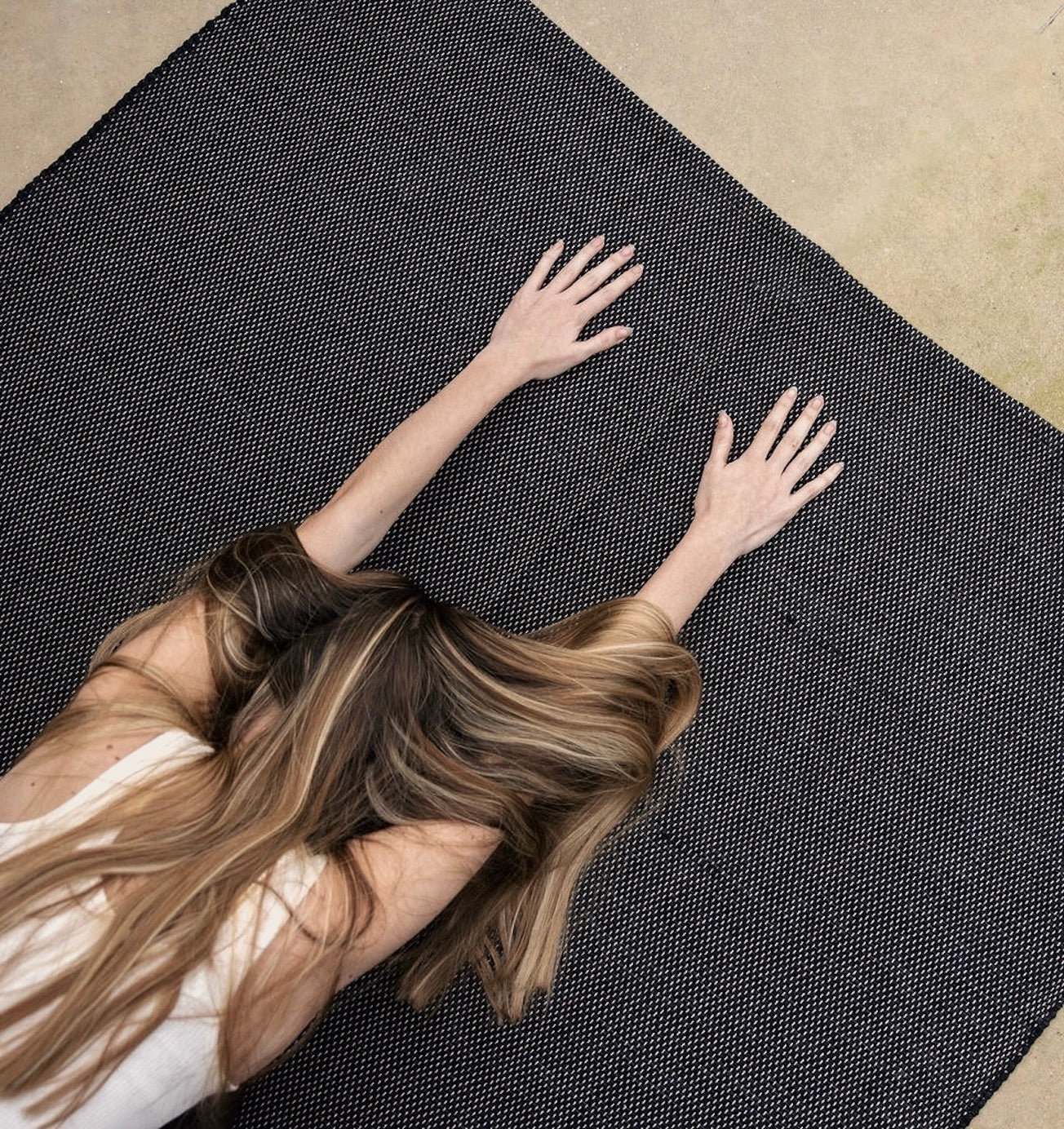 woman in childs pose with hands on Rituil non slip natural ash or black recycled cotton yoga rug #color_ash