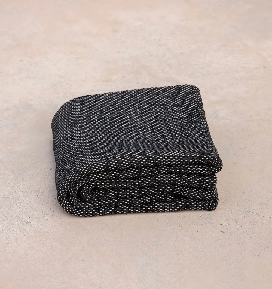 ⁠Heavyweight and oversized sustainable recycled cotton yoga rug in black folded on a studio floor. #color_ash
