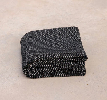 ⁠Heavyweight and oversized sustainable recycled cotton yoga rug in black folded on a studio floor. #color_ash