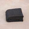 ⁠Heavyweight and oversized sustainable recycled cotton yoga rug in black folded on a studio floor. #color_ash