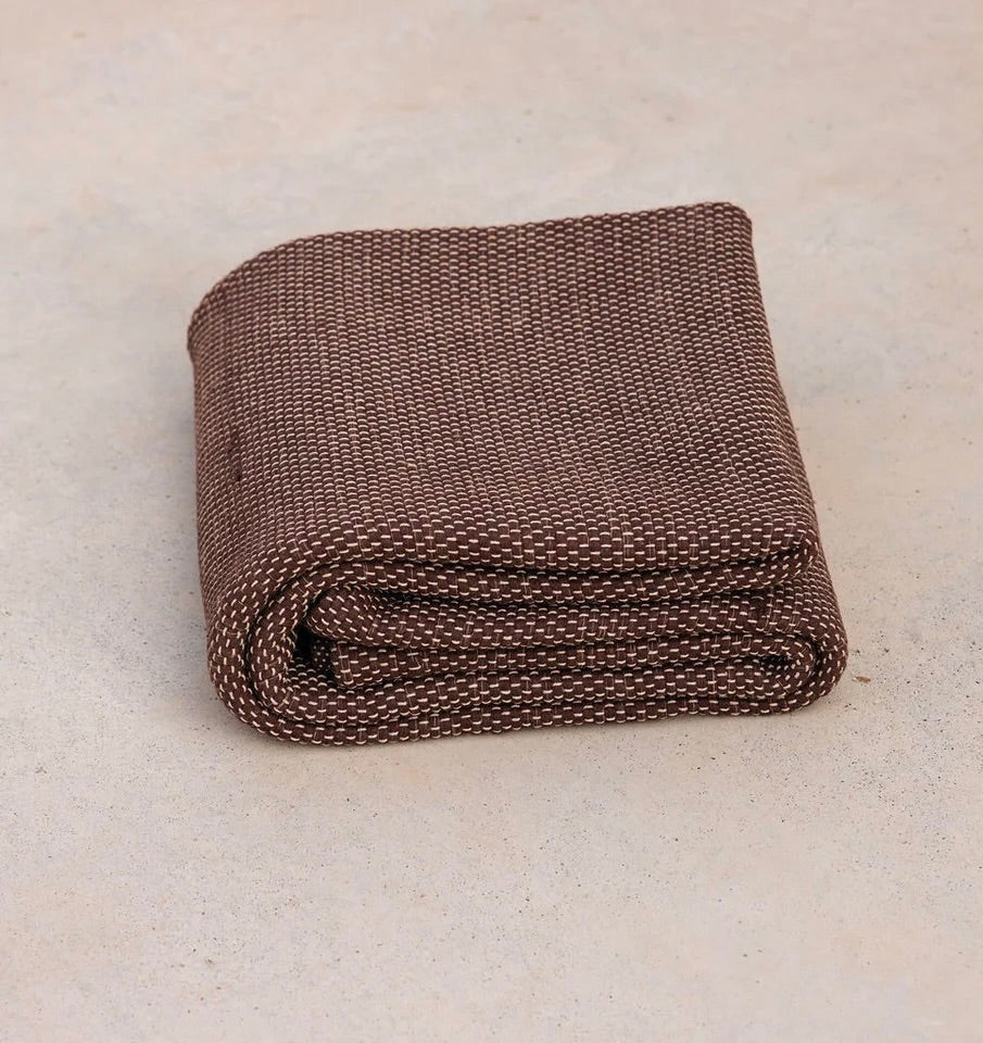 Oversized sustainable recycled cotton restorative yoga rug in brown color from Rituil folded on studio floor #color_earth