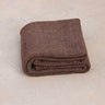Oversized sustainable recycled cotton restorative yoga rug in brown color from Rituil folded on studio floor #color_earth