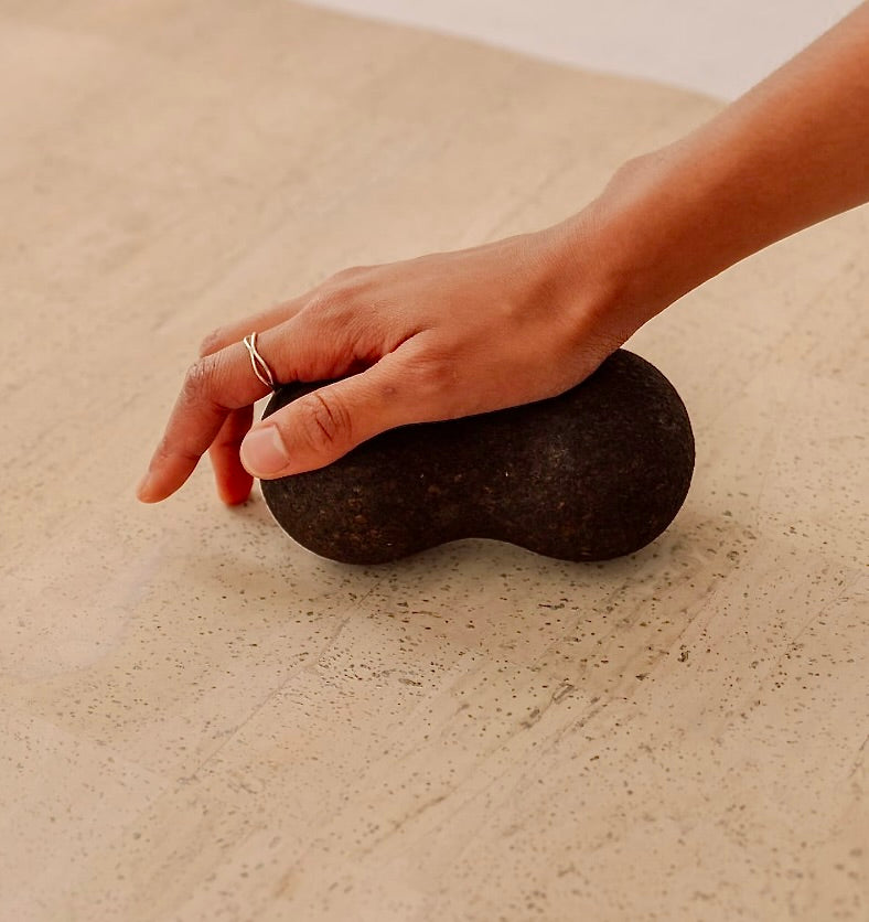 Rituil sustainable Portuguese cork massge peanut for yoga, Pilates core workouts, and deep tissue muscle recovery shown wiht womans hand pressing into peanut on cork yoga mat
