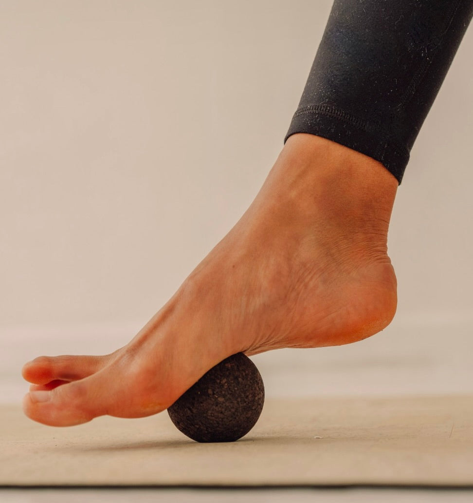 Rituil sustainable Portuguese cork massge ball pressing into woman foot on top of cork yoga mat
