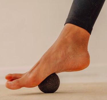 Rituil sustainable Portuguese cork massge ball pressing into woman foot on top of cork yoga mat