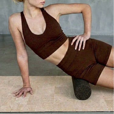 woman using Rituil cork massage roller on cork. yoga mat